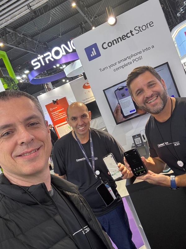 Three ACSN team members at the ConnectStore booth at MWC 2025, two of them showing the app on phones.